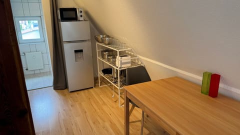 Esstisch, Kühlschrank, Mikrowelle und Zubehör.