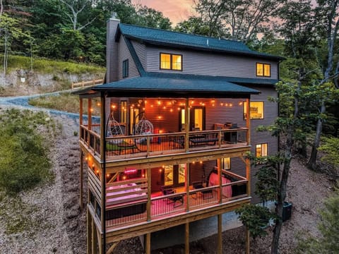 Spacious 3-story cabin glowing warmly among the trees at dusk