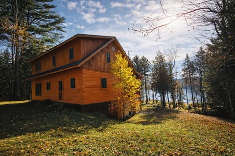 Secluded lakeview cabin surrounded by towering pines and colorful fall foliage, offering a peaceful wooded setting just steps from the water.