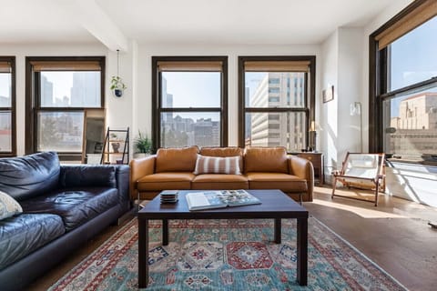 Enjoy natural sunlight in this beautifully designed living area, featuring comfy seating and vibrant city views. The couches can also accommodate two additional guests for a cozy stay.