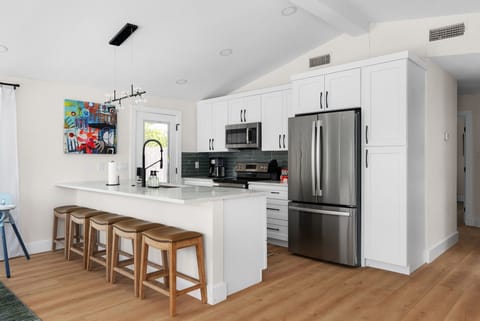 Featuring a microwave, fridge, stove, and coffee maker. The sleek white cabinets add a touch of elegance to this inviting environment. Whether you're an experienced chef or just starting out, this kitchen has everything you need for cooking success!