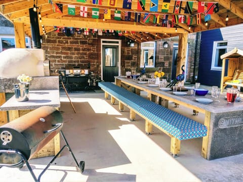 All weather BBQ space off kitchen, padded bench seating and festoon lighting.