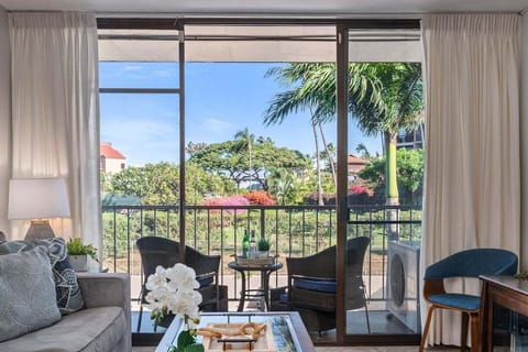 Living room with sliding doors to a balcony overlooking lush greenery.