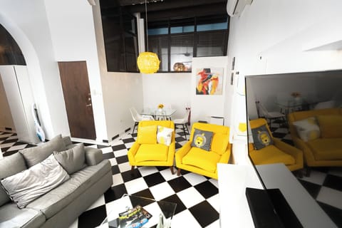 living room with large grey sofa and cushions, two sofa seatn, smart tv, coffee table, dining table with 4 seats, wall art, ceiling lamp