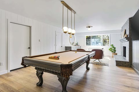 Downstairs game room with billiards, seating area, gas fireplace, and smart TV.