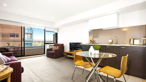 Bright open layout combining a minimalist kitchen, dining, and balcony access.