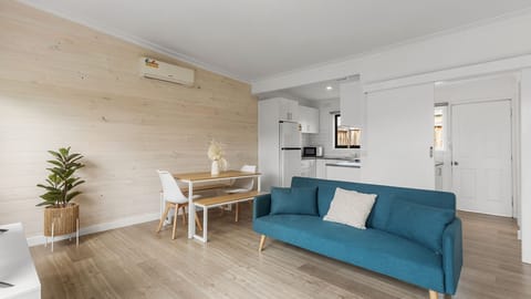Relax in the stylish open-plan lounge, filled with natural light and featuring a comfortable sofa and warm timber finishes.