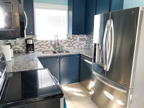 Modern kitchen with stainless steel appliances and blue cabinets.
