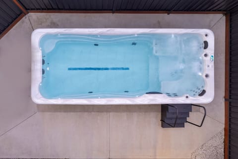 Indulge in the luxury of your very own heated swim spa, a tranquil outdoor feature designed for relaxation and rejuvenation. Nestled amidst lush greenery, this swim spa offers the perfect escape after a long day. Enjoy a soothing spa or a refreshing swim.