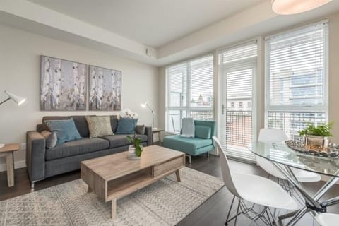 Bright living room with floor-to-ceiling windows and cozy sofa convertible into a queen bed!