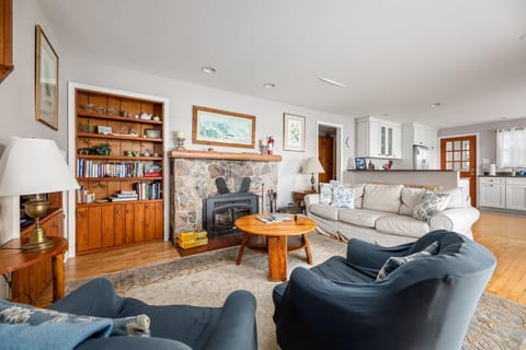 A warm and inviting living room with a stone fireplace, cozy seating, and a built-in bookshelf. Perfect for relaxing after a long day.