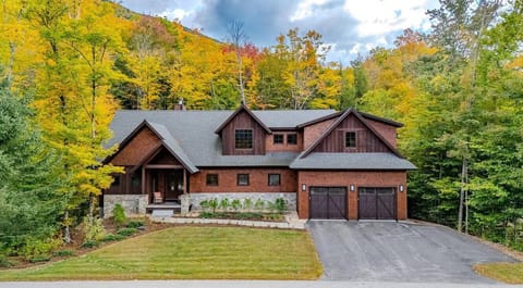 Beautiful mountain retreat surrounded by vibrant fall foliage, featuring a rustic wood exterior, large windows, and a cozy front porch. Perfect for a peaceful getaway in the heart of the White Mountains.