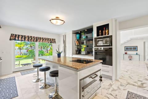 Bright and airy kitchen with an island, bar stools, and a scenic view, creating an ideal space for gathering.