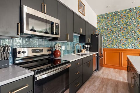A sleek, modern kitchen with stainless steel appliances, dark cabinetry, and a colorful tile backsplash, offering both style and functionality.