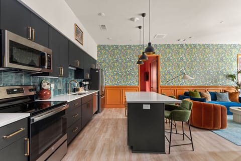 A sleek, modern kitchen with stainless steel appliances, dark cabinetry, and a colorful tile backsplash, offering both style and functionality.