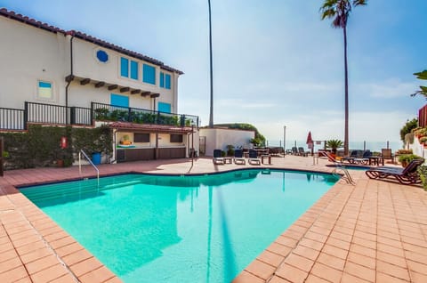 Sunny pool area w/ lounge chairs & open deck space, perfect for cooling off & relaxing outdoors