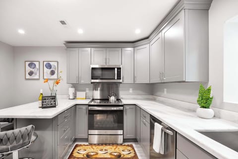 Spacious, modern kitchen with sleek gray cabinetry, stainless steel appliances, and pristine marble countertops. The open layout and bright design make it a perfect space for cooking and entertaining.