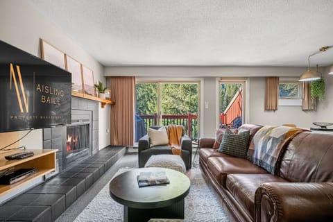 Living room with a smart TV with cable, a decorative fireplace, and cozy seating options with a queen-sized pull-out sofa bed.