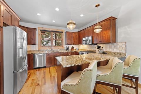 Full kitchen with stainless steel appliances, and breakfast bar seating 3.