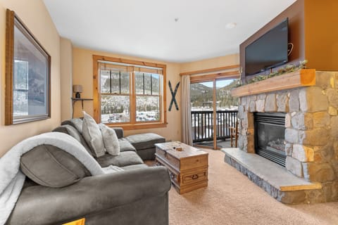 Unwind by your cozy stone fireplace while mountain views frame your perfect alpine retreat through panoramic windows.