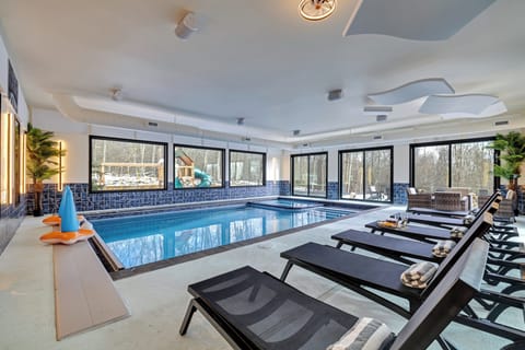 Heated indoor pool with loungers and wall-to-wall windows