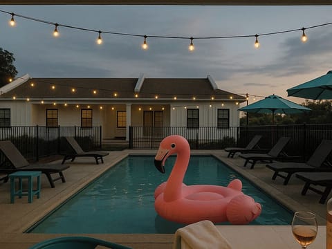 String lights twinkle overhead as a pink flamingo float drifts in the pool, setting the mood for a perfect evening retreat.