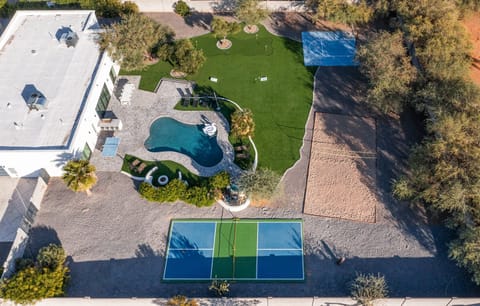 Giant Backyard featuring a pool, mini golf, cornhole, basketball court, sand volleyball, pickleball court, ping pong table, sun loungers, fire pit, grill, and dining table with seating for 10 guests.