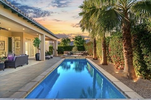 Relax by the long sparkling pool lined w/ palms & cozy outdoor seating at sunset