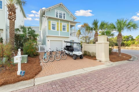 Charming coastal-style home with golf cart and bikes ready for beach adventures in this palm-lined neighborhood.