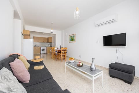 Open-plan living room with sofa, dining area, kitchen, A/C, WiFi internet, and satellite TV