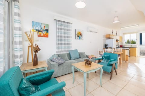 Open-plan living room with sofa, dining area, kitchen, A/C, WiFi internet, and satellite TV