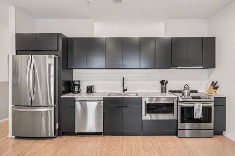 Sleek modern kitchen with matte black cabinets, marble counters, and stainless appliances.