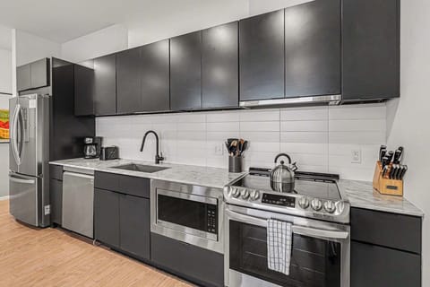 Sleek modern kitchen with matte black cabinets, marble counters, and stainless appliances.