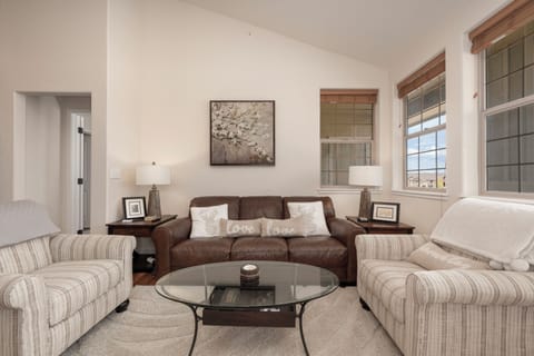 Sink into plush seating around your glass coffee table, where love-themed pillows invite cozy conversations in this bright, welcoming living space.