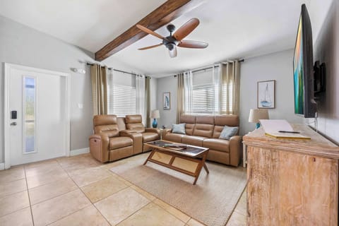 Relax in the modern living room featuring leather recliners and a mounted flat-screen TV.