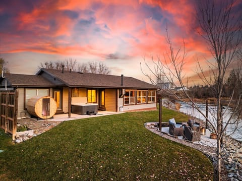 Unwind in the tranquil backyard oasis featuring a private hot tub, sauna, and fire pit overlooking the serene river. Perfectly located in Kalispell, MT, near Glacier National Park and Whitefish, this retreat offers relaxation and adventure.