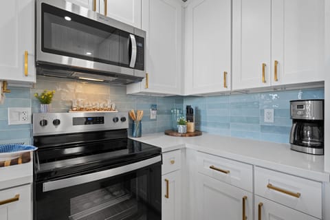 Stylish quartz countertops, personalized tile backsplash, and stunning white cabinets