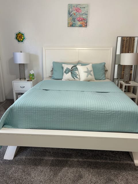 Queen bed, bedside tables with lamps, and chair in room. Attached bathroom.