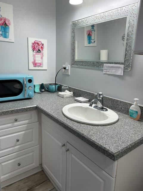 Microwave on counter in attached bathroom. 