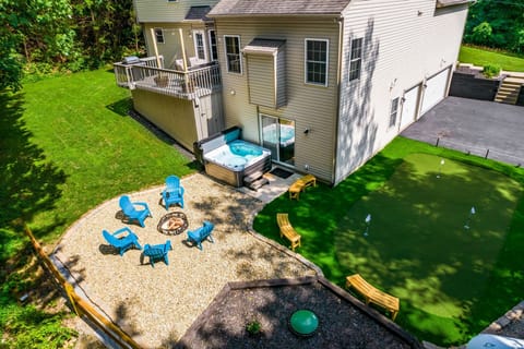 Tranquil backyard with hot tub, putt-putt green, and forest backdrop.