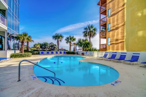 Outdoor pool area with palm trees and abundant lounge chair