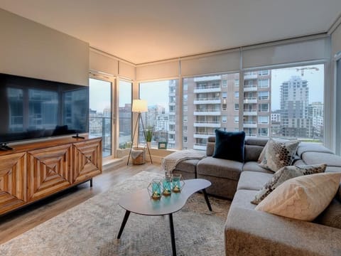 Sunlit living room with panoramic city views, cozy sofa, and smart TV