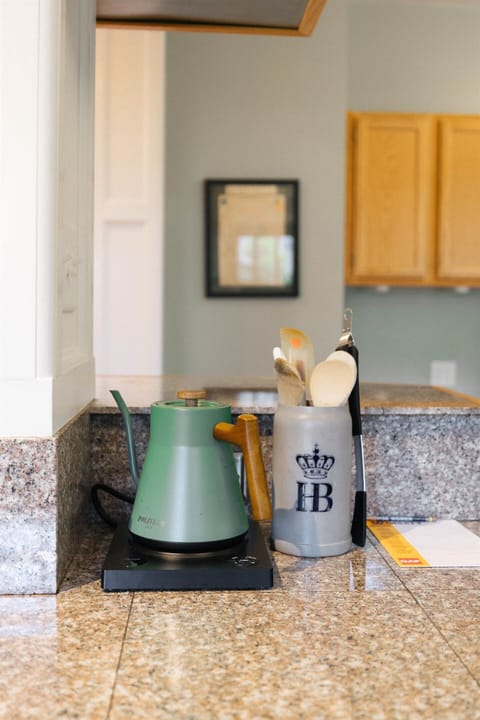 Cozy kitchen corner with a stylish green kettle and utensil holder, perfect for a homey cooking experience.
