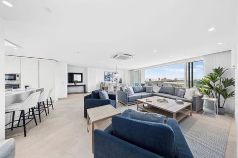 Your spacious open-plan living area features comfortable seating, stylish decor, modern kitchen facilities, and stunning city views through expansive windows that flood the space with natural light.