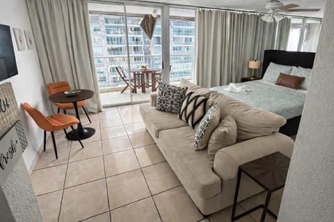 Bright and inviting studio featuring a comfortable queen bed, cozy seating area, and private balcony perfect for morning coffee or evening relaxation.