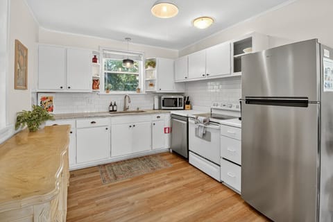 Cook and gather in a fully equipped kitchen with stainless steel appliances, open shelving, and warm natural light.
