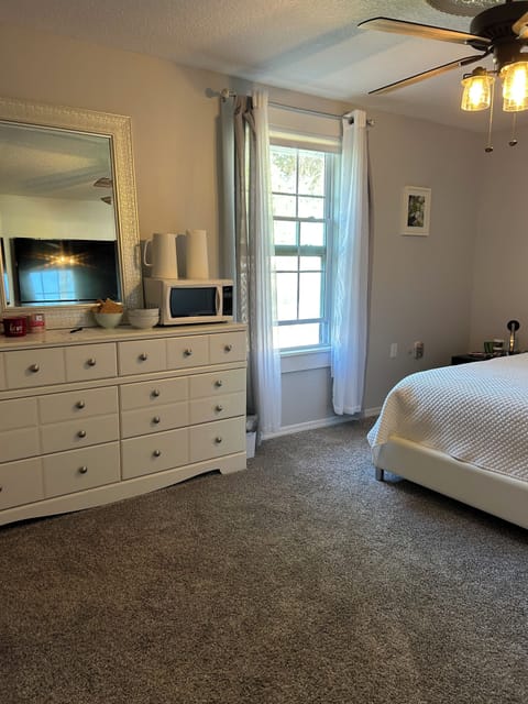 Bedroom with ceiling fan, microwave, electric kettle and attached bathroom.