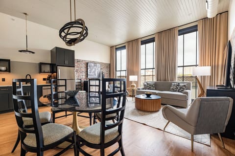 Charming living space featuring preserved brick walls and floor-to-ceiling windows, offering an inviting blend of character and light.