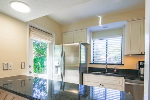 The kitchen features white cabinets and a stainless steel refrigerator and dishwasher.