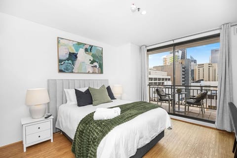 Come to a comfortable bedroom featuring a plush bed, complemented by green and black pillows and elegant artwork, offering a serene personal space.